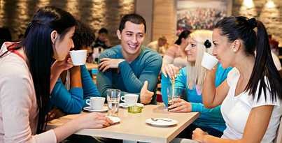 fünf Jugendliche sitzen in einem Café und trinken aus Tassen