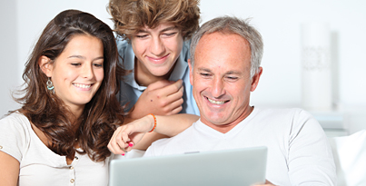 zwei jugendliche und eine erwachsene Person schauen auf einen Laptop